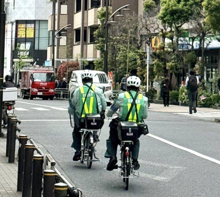 緑の制服を着た駐車監視員（緑のおじさん）が巡回している様子。